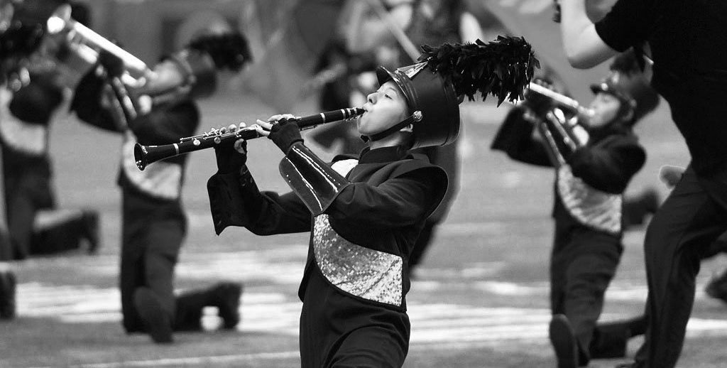 Black and white photo of a marching band member playing a trumpet.